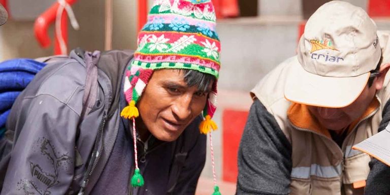 Two man wearing colorful adornments standing around  two workers